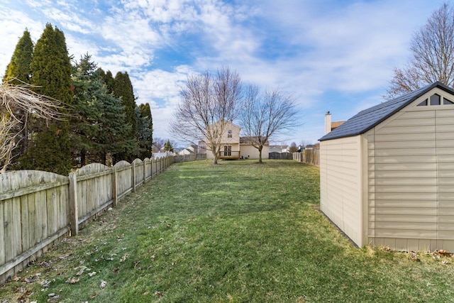 view of yard with an outbuilding, a fenced backyard, and a storage shed