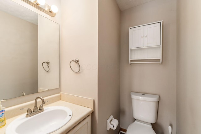 bathroom with toilet, a textured ceiling, and vanity