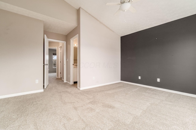 unfurnished room featuring light carpet, baseboards, vaulted ceiling, and a ceiling fan