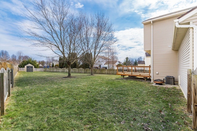 view of yard with a deck, a fenced backyard, central AC, an outdoor structure, and a storage unit