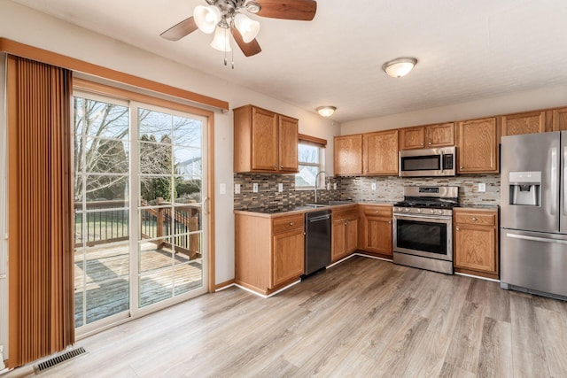 kitchen featuring tasteful backsplash, visible vents, stainless steel appliances, light wood-style floors, and a sink