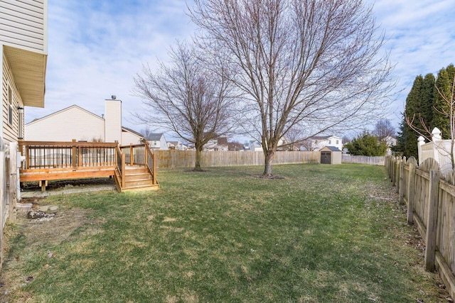 view of yard featuring a fenced backyard, a shed, a deck, and an outbuilding