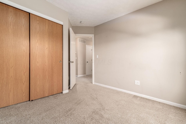 unfurnished bedroom featuring visible vents, baseboards, a closet, and carpet flooring