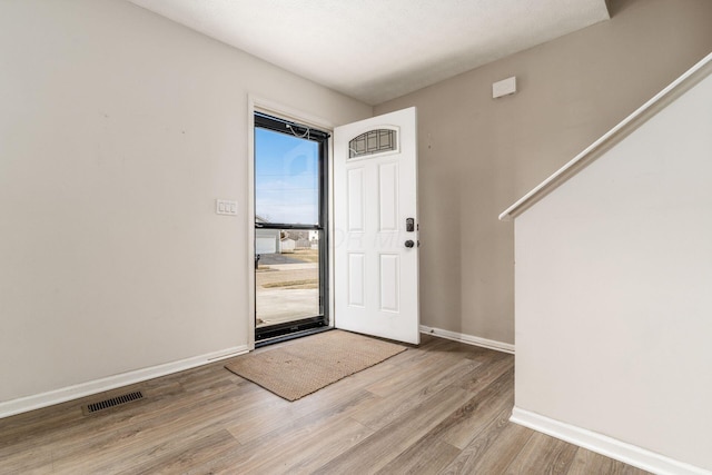 entryway with wood finished floors, visible vents, and baseboards