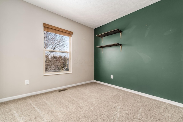 unfurnished room featuring carpet, visible vents, baseboards, and a textured ceiling