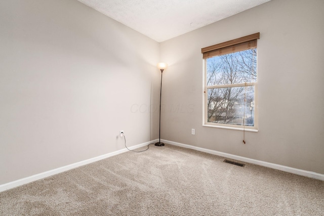 empty room with carpet floors, baseboards, visible vents, and a textured ceiling