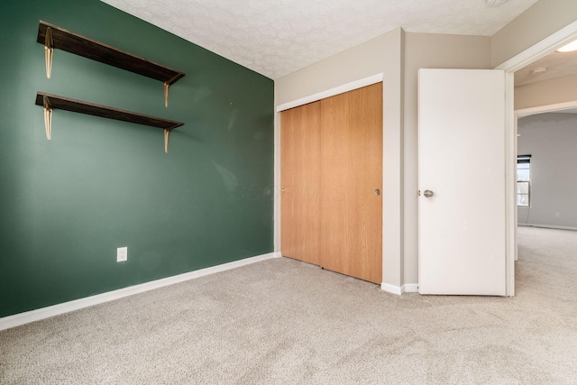 unfurnished bedroom featuring carpet floors, a closet, baseboards, and a textured ceiling