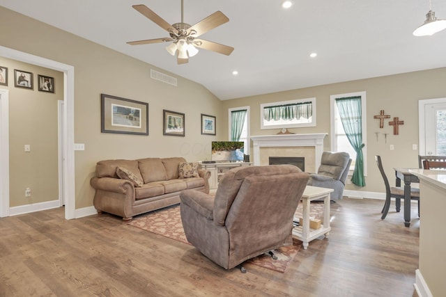 living area with baseboards, visible vents, lofted ceiling, wood finished floors, and a fireplace