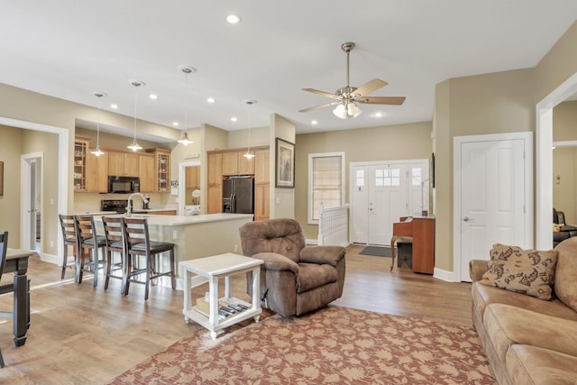 living area featuring light wood-style floors, baseboards, a ceiling fan, and recessed lighting