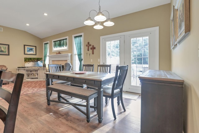 dining room with french doors, a fireplace, lofted ceiling, recessed lighting, and light wood-style flooring