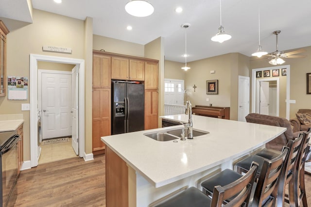 kitchen with a breakfast bar area, black refrigerator with ice dispenser, a sink, ceiling fan, and dishwasher