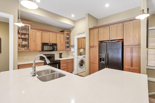 kitchen with a sink, light countertops, backsplash, black appliances, and washer / dryer