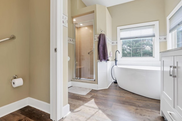 full bath with a freestanding bath, baseboards, wood finished floors, and a shower stall