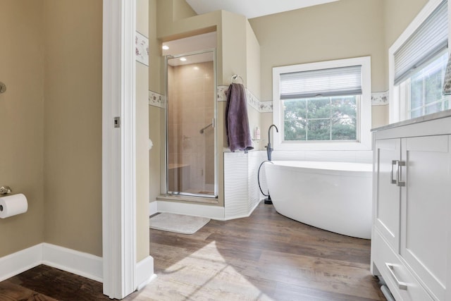 full bathroom with a stall shower, a freestanding bath, baseboards, and wood finished floors