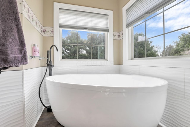 full bath with a freestanding tub and tile walls