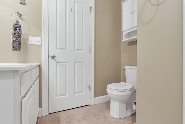 half bathroom with toilet, tile patterned flooring, baseboards, and vanity