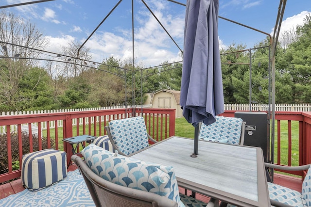 wooden deck with a fenced backyard, an outbuilding, a yard, a shed, and outdoor dining space