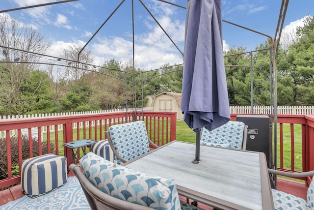 wooden deck featuring outdoor dining area, a fenced backyard, a storage shed, an outdoor structure, and a yard