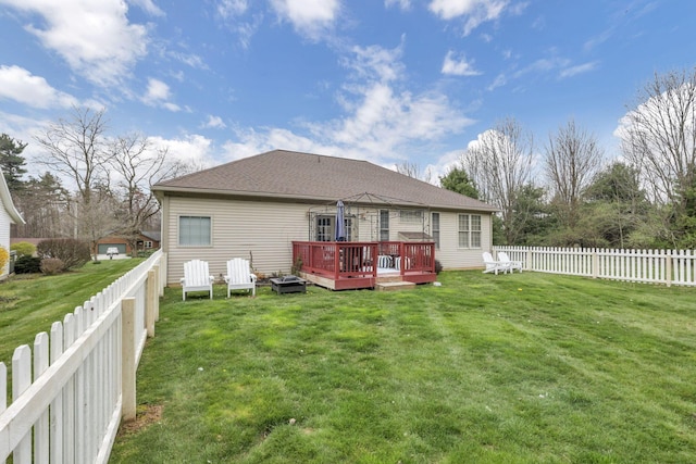 back of house featuring a deck, a shingled roof, a lawn, and a fenced backyard