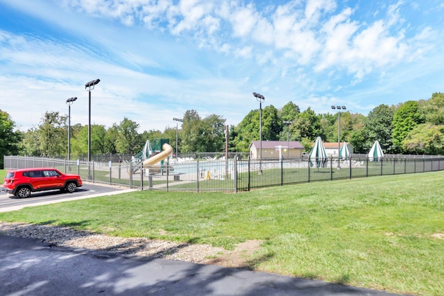 surrounding community featuring playground community, a lawn, and fence