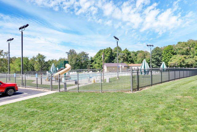 view of property's community with a yard, playground community, and fence