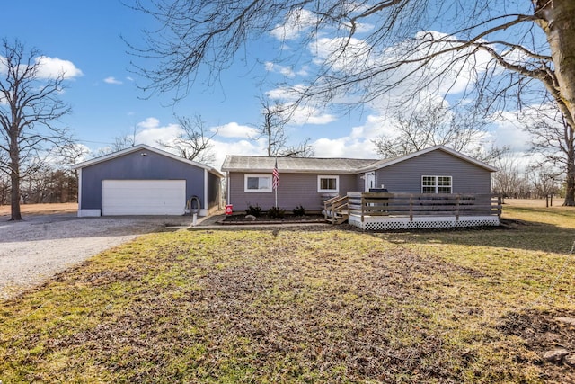 view of front facade with a garage, a front yard, a deck, and an outbuilding