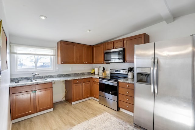 kitchen with lofted ceiling with beams, stainless steel appliances, a sink, light wood-type flooring, and brown cabinets