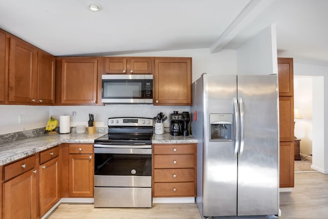 kitchen featuring light wood-style floors, appliances with stainless steel finishes, and brown cabinetry