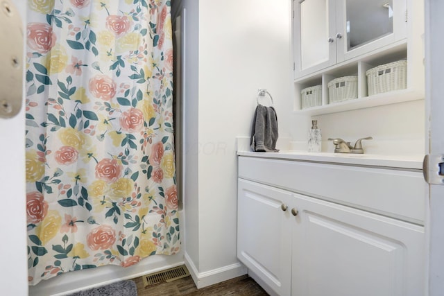 full bathroom featuring visible vents, shower / bath combo with shower curtain, vanity, wood finished floors, and baseboards