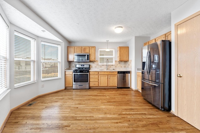 kitchen with light brown cabinets, a sink, light countertops, appliances with stainless steel finishes, and light wood-type flooring