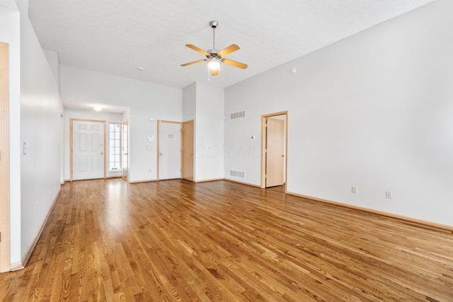 unfurnished living room featuring a textured ceiling, ceiling fan, visible vents, and light wood-style floors