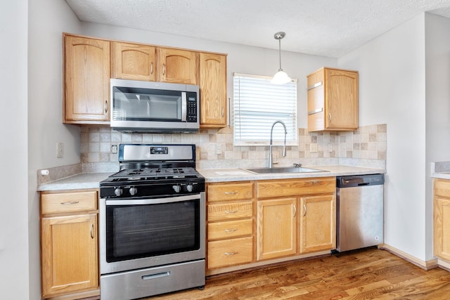 kitchen featuring light brown cabinets, stainless steel appliances, a sink, and light countertops