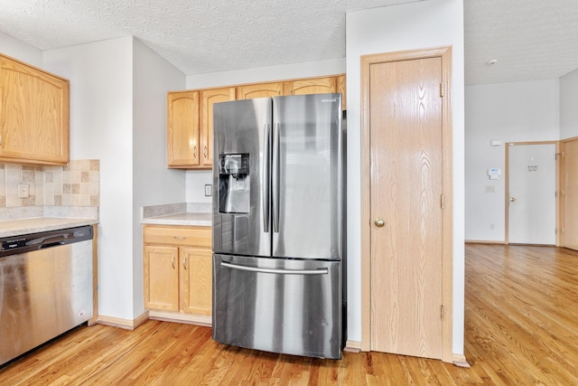 kitchen with stainless steel appliances, light countertops, light brown cabinets, and light wood-style floors