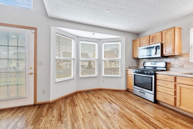 kitchen with stainless steel appliances, light brown cabinets, and light wood finished floors