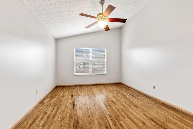 empty room featuring ceiling fan, a textured ceiling, light wood-style flooring, baseboards, and vaulted ceiling