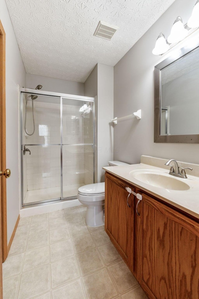 full bathroom featuring visible vents, toilet, tile patterned floors, vanity, and a shower stall