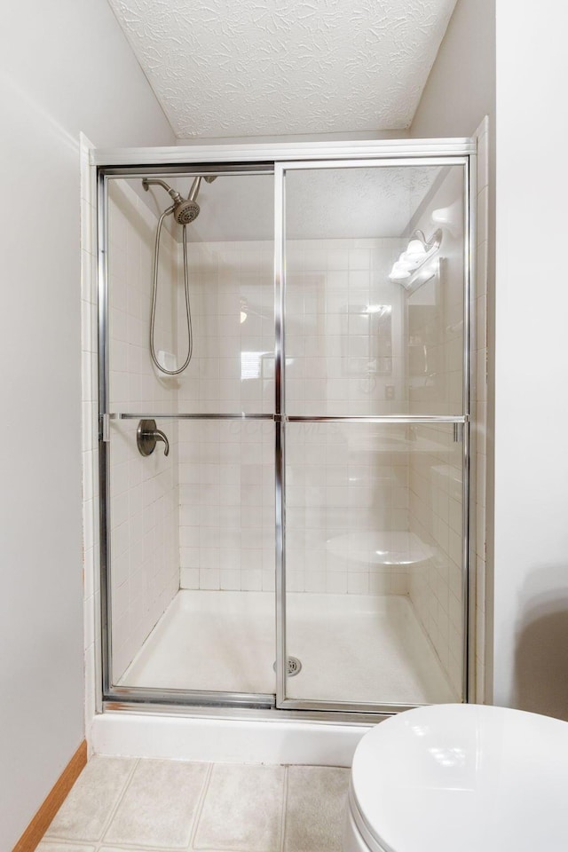 full bath with a stall shower, a textured ceiling, and tile patterned floors