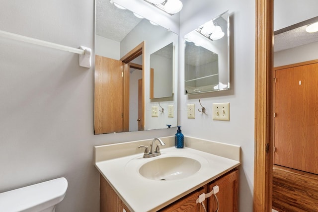 bathroom with toilet, a textured ceiling, and vanity