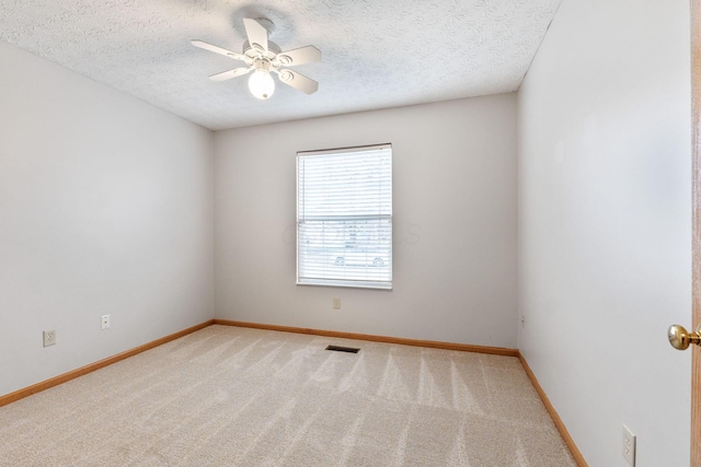 carpeted empty room with a ceiling fan, visible vents, a textured ceiling, and baseboards