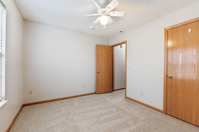 unfurnished bedroom featuring a textured ceiling, ceiling fan, carpet flooring, and baseboards