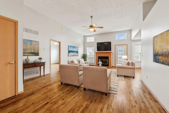 living area with light wood-style floors, visible vents, a fireplace, and a textured ceiling