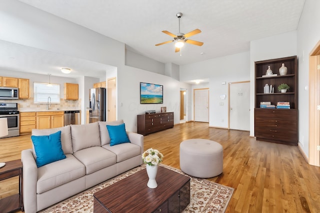 living area with baseboards, a ceiling fan, and light wood-style floors