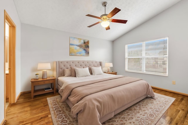 bedroom with a textured ceiling, a ceiling fan, baseboards, vaulted ceiling, and light wood finished floors