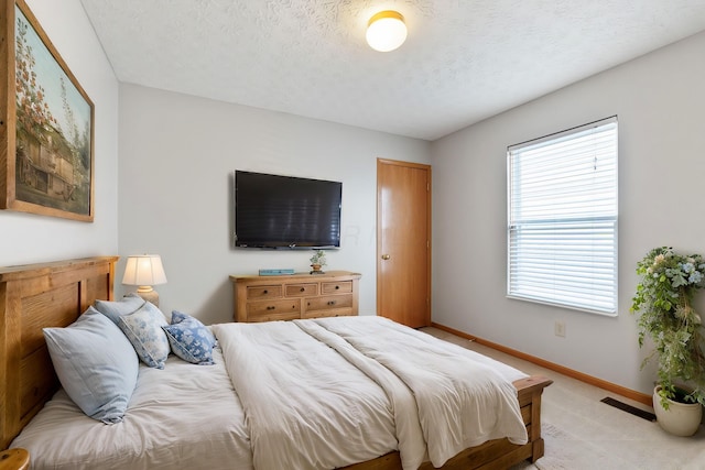 bedroom featuring baseboards, visible vents, a textured ceiling, and light colored carpet