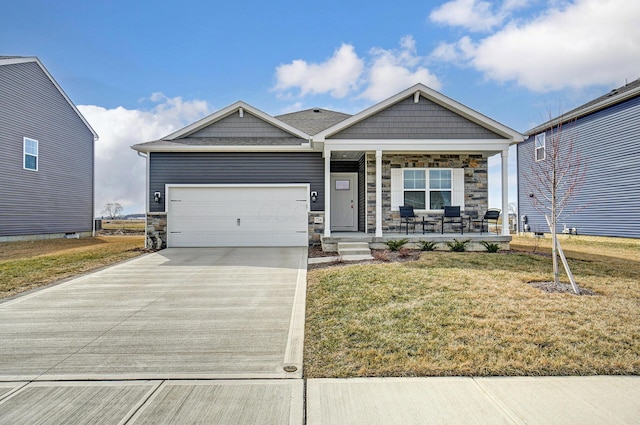 craftsman house featuring an attached garage, covered porch, stone siding, driveway, and a front yard