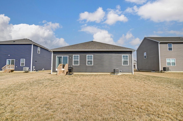 back of property with central AC and a lawn