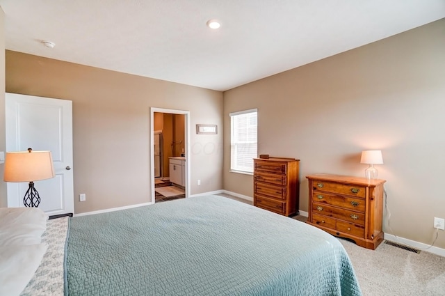 carpeted bedroom featuring ensuite bath, visible vents, and baseboards