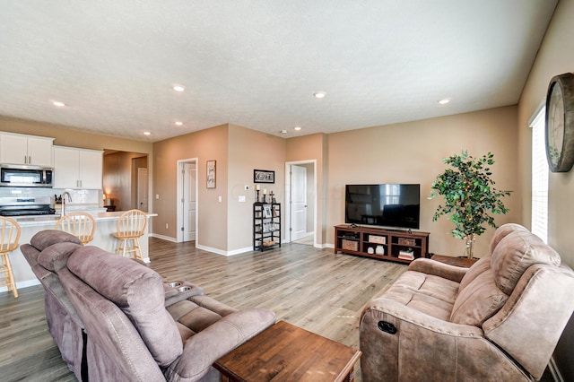 living room featuring recessed lighting, light wood-style flooring, and baseboards