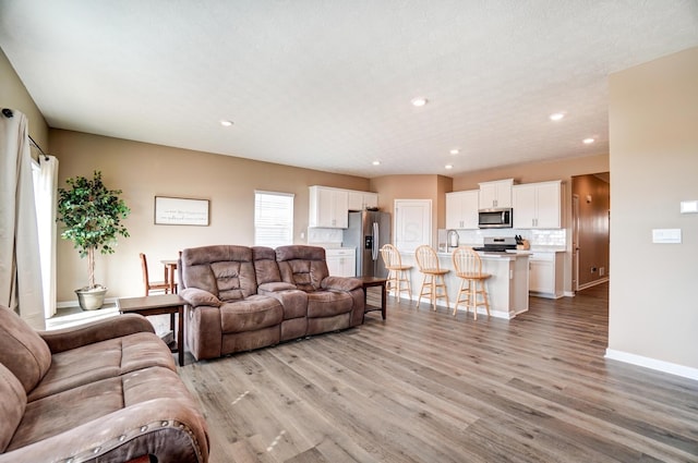 living room with light wood-style floors, baseboards, and recessed lighting