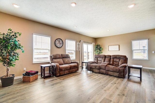 living area with a textured ceiling, recessed lighting, baseboards, and light wood-style floors